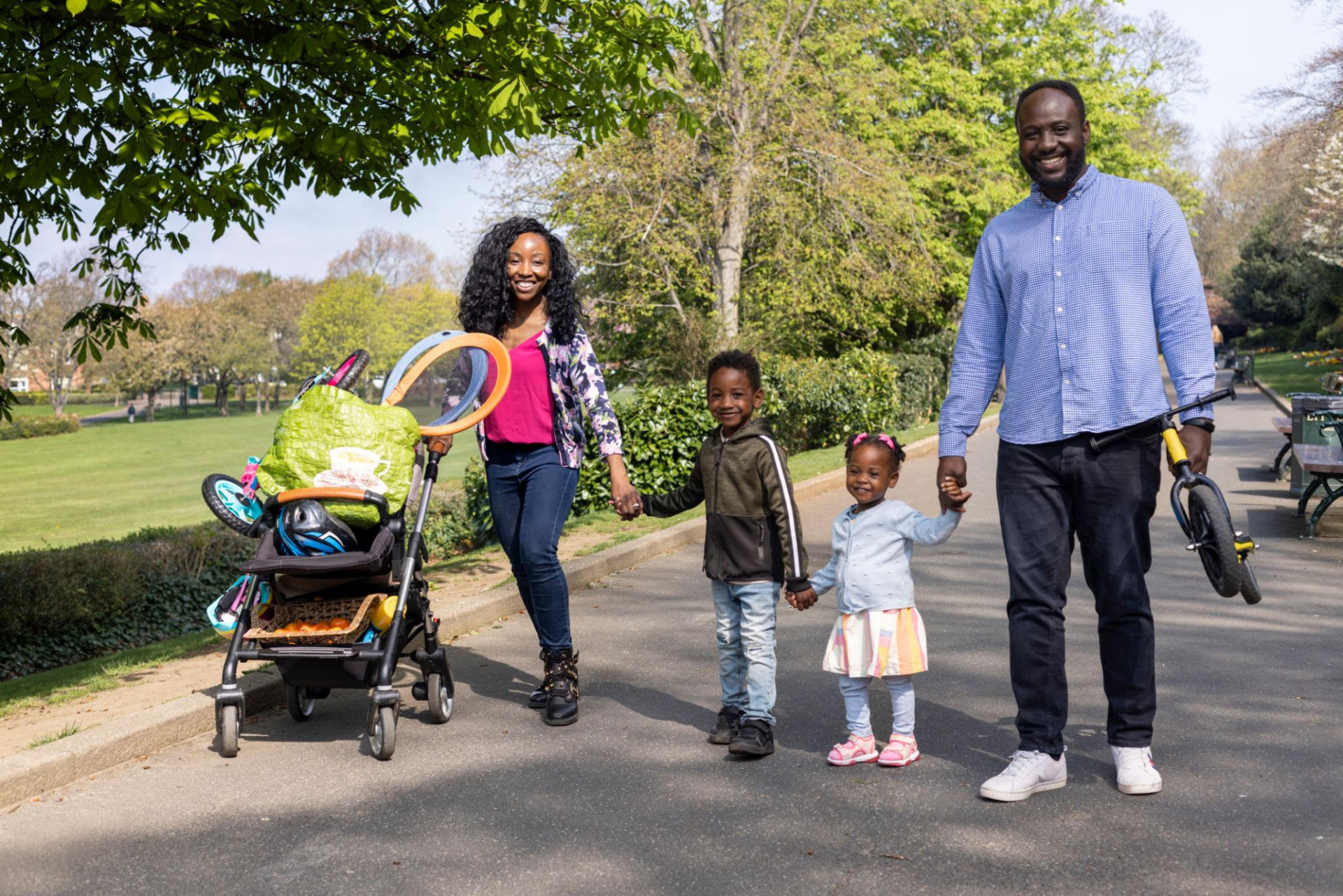 A family walking hand in hand through a neighborhood park